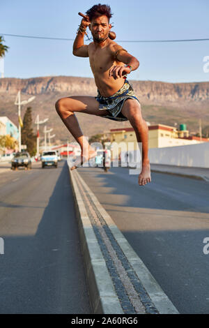 L'homme Tribal avec son arc et flèches traditionnelles de sauter sur une bande médiane, Lubango, Angola Banque D'Images