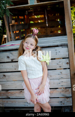 Fille vêtue comme une princesse avec couronne et sceptre jouant dans une maison d'arbre Banque D'Images