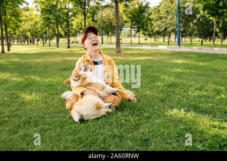 Laughing boy avec Welsh Corgi Pembroke dans un parc Banque D'Images