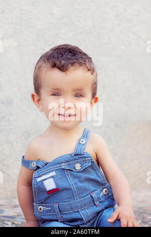 Portrait of little boy wearing denim salopettes en été Banque D'Images