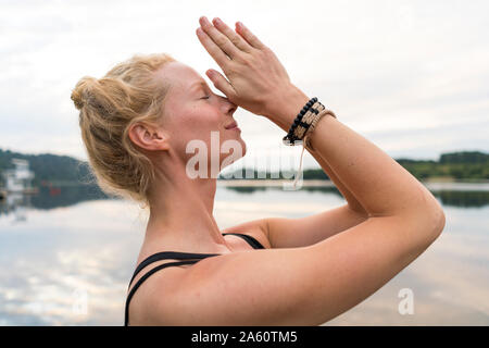 Jeune femme aux mains jointes à un lac Banque D'Images