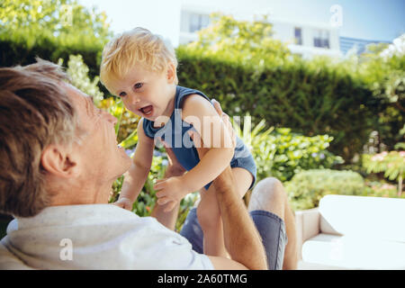 Père assis dans le jardin, jouant avec son petit-fils Banque D'Images