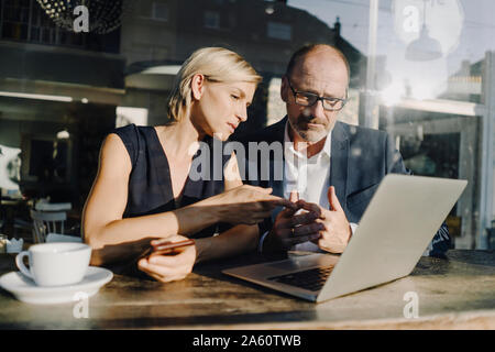 Businessman and woman sitting in coffee shop, using laptop Banque D'Images