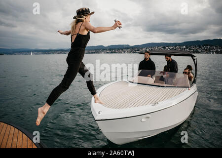 Jeune femme sautant sur un bateau sur un lac Banque D'Images