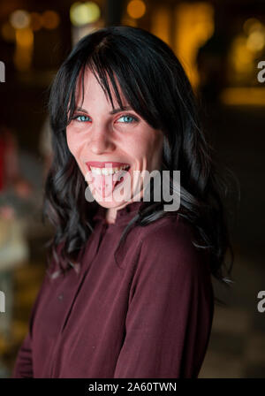 Portrait d'une jeune femme dans la ville sticking out tongue dans la nuit Banque D'Images