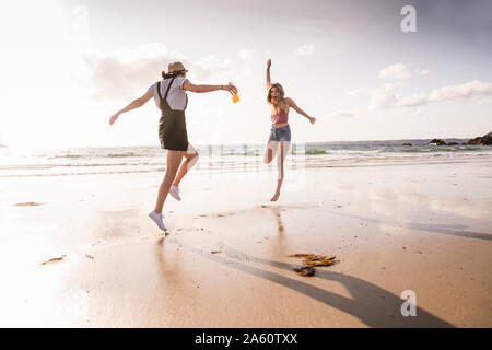 Deux copines s'amuser, courir et sauter sur la plage Banque D'Images