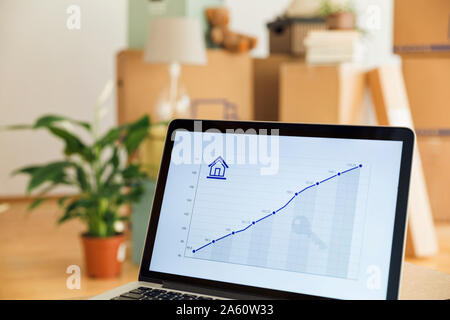 La ligne graphique sur un écran d'ordinateur portable en face de boîtes de carton dans une nouvelle maison Banque D'Images