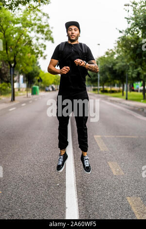 Jeune homme sautant en l'air sur une rue Banque D'Images