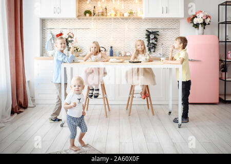 Fivechildren de manger des cookies dans la cuisine Banque D'Images