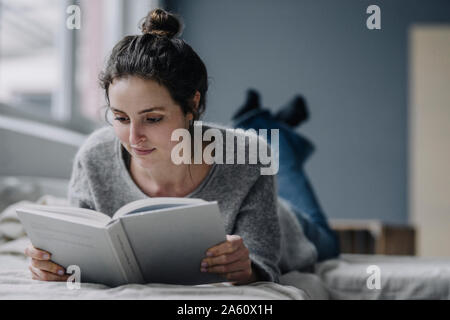 Portrait of young woman reading book at home Banque D'Images