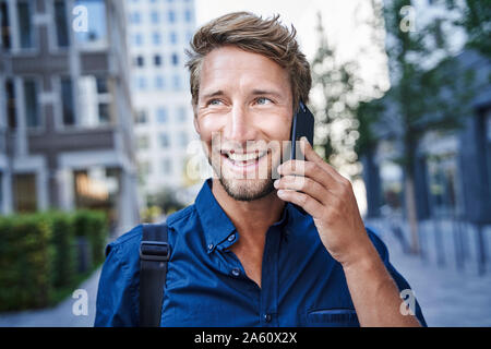 Portrait of happy young businessman au téléphone dans la ville Banque D'Images