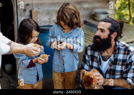 Père de deux enfants et les poussins de poulet tenant sur une ferme biologique Banque D'Images