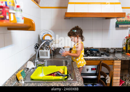 Petite fille lave-vaisselle dans la cuisine à la maison Banque D'Images