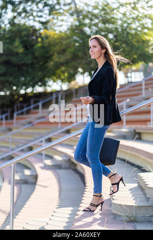 Avec un sac à main femme descendant des escaliers Banque D'Images