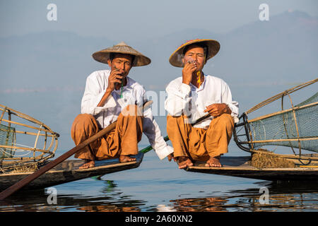 Deux pêcheurs aviron jambe ethnie Intha fumer des cigares, au Lac Inle, l'État de Shan, Myanmar (Birmanie), l'Asie Banque D'Images