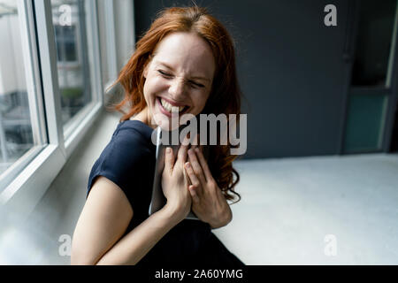 Portrait de femme rousse riant avec tablette numérique dans un loft Banque D'Images