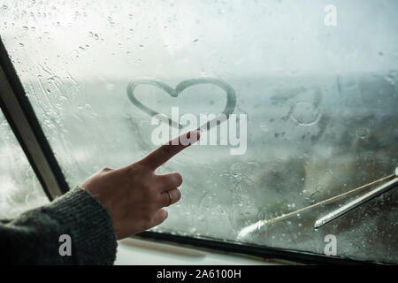 Le doigt de Femme dessinant un coeur sur la fenêtre d'un van Banque D'Images