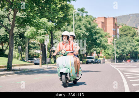Jeune couple vintage scooter sur route urbaine Banque D'Images