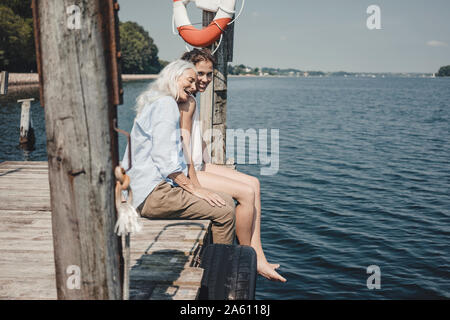 Mother and Daughter sitting on Jetty, détente à la mer Banque D'Images