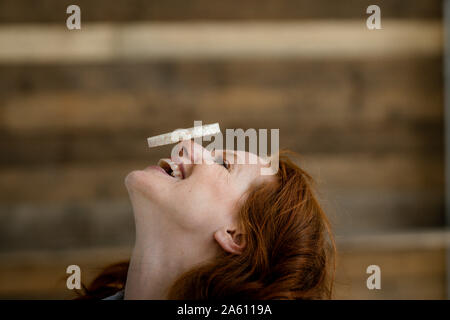 Laughing woman balancing gâteau de riz sur son nez Banque D'Images