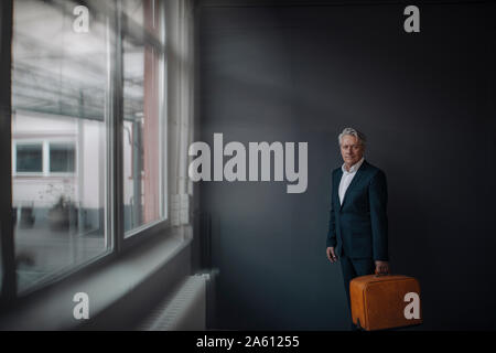 Senior businessman holding old-fashioned suitcase Banque D'Images