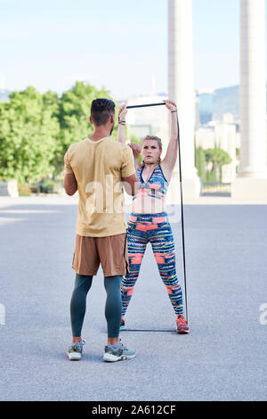 Coach de remise en forme pratiquant avec jeune femme à l'extérieur dans la ville Banque D'Images