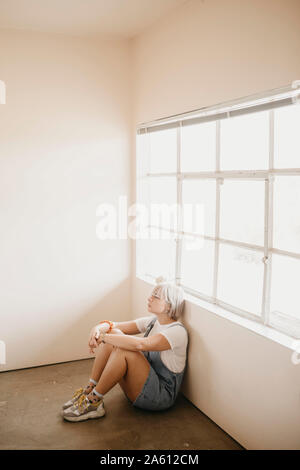 Jeune femme assise sur le sol dans une chambre Banque D'Images