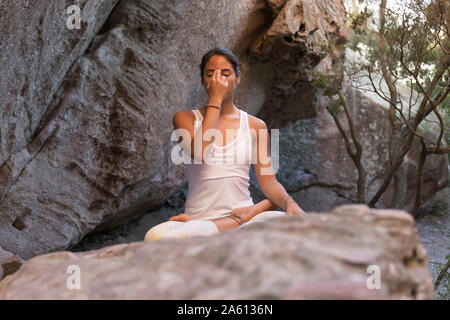 Young Asian woman practicing yoga on a rock, la respiration Banque D'Images