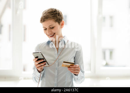 Happy woman using cell phone, une carte de crédit Banque D'Images