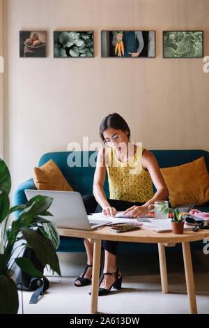 Fashion designer sitting on couch travailler sur une nouvelle collection Banque D'Images