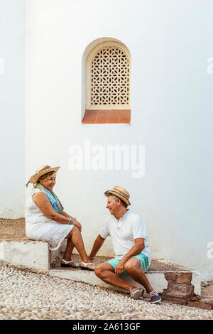 Happy tourist couple sitting on steps dans un village, El Roc de Sant Gaieta, Espagne Banque D'Images