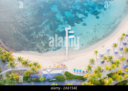 Jetty et transats sur la plage bordée de palmiers, baignée par la mer des Caraïbes à partir de ci-dessus par drone, Morris Bay, Old Road, Antigua, Iles sous le vent, West Indies Banque D'Images