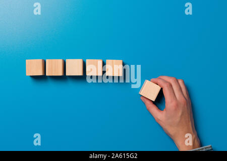 Woman's hand établit une ligne de cubes en bois. Blocs de bois vierge pour Word, texte ou d'illustration. Placer la main et la ligne de finition cube Banque D'Images