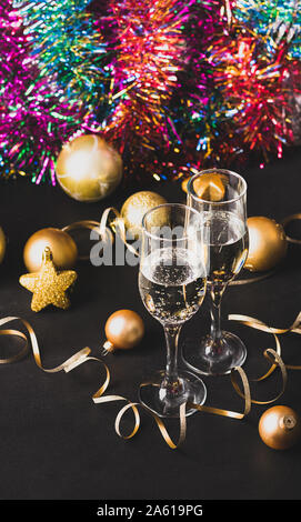 Deux verres de champagne or de noël jouets star serpentine boules sur un fond noir. Noël Nouvel An concept. Le minimalisme de fête. F verticale Banque D'Images