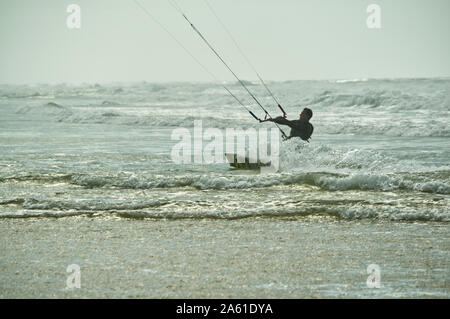 Kite surfer l'écrémage dans les eaux peu profondes de la plage avec des vagues se brisant sur la côte Atlantique à Argelès-sur-Mer, France Banque D'Images