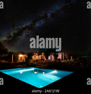 La voie laiteuse et le ciel de nuit au-dessus d'une maison lumineuse villa et piscine. Algarve Portugal Banque D'Images