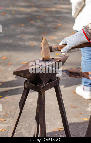 Un forgeron forge un metal vide sur l'enclume à un juste dans la présence de spectateurs. Close-up. Banque D'Images