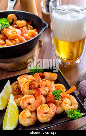 Crevettes grillées savoureuses avec un verre de bière sur la table en bois Banque D'Images