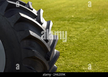 Close up de pneu du tracteur, selective focus. roue sur un fond d'herbe verte Banque D'Images