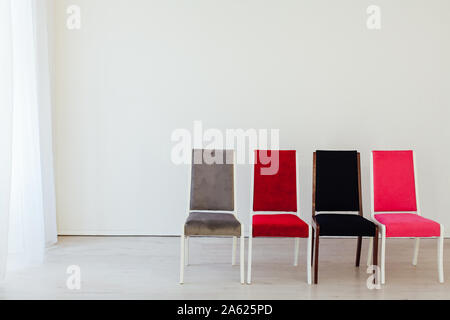 Chaises multicolores à l'intérieur d'une chambre blanche vide Banque D'Images