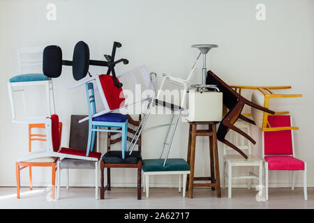 De nombreuses chaises multicolores dans le désordre de la chambre blanche