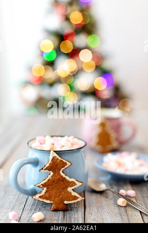 Joyeux Noël ! En forme d'arbre de Noël gingerbread cookie près de tasses de cacao et les guimauves. Bel arbre de Noël avec l'arrière-plan flou lumino Banque D'Images