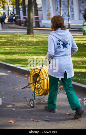 Kharkiv, Ukraine - le 14 octobre 2019 : Un employé d'un parc de la ville est porteur d'un panier avec un tuyau pour arroser les plantes Banque D'Images