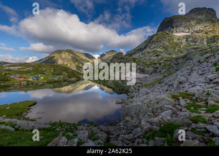 Un paysage extraordinaire dans la montagne bulgare, réflexion du ciel dans le lac et tentes autour du lac de montagne de Rila en Bulgarie. Banque D'Images