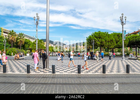 Les touristes profitez d'une agréable journée sur la côte d'Azur comme ils flâner Place Massena avec Promenade du Paillon water park dans la distance à Nice France Banque D'Images