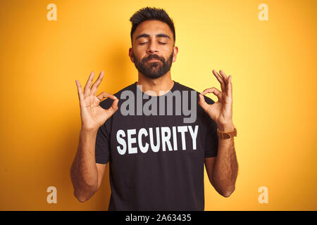 Sauvegarde hispanique indienne arabe homme portant un uniforme de sécurité sur fond jaune isolé vous détendre et souriant avec les yeux fermé faisant la méditation gestur Banque D'Images