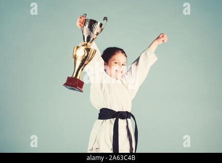 Le succès du sport. La formation pour être le meilleur. Petite fille avec champion cup. arts martiaux Kung Fu pratique. enfance heureuse. winner petite fille dans gi sportswear. Masquage. l'énergie et de l'activité pour les enfants. Banque D'Images