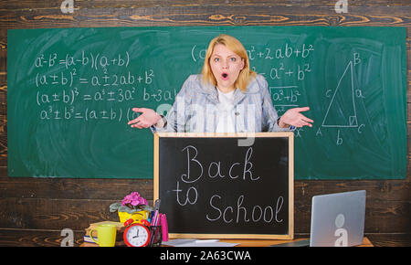 L'école. L'enseignement à domicile. surpris femme. Retour à l'école. Journée des enseignants. enseignant avec réveil au tableau noir. Le temps. femme en classe. L'étude et l'éducation. L'école moderne. Jour des connaissances. Regardez ceci. Banque D'Images