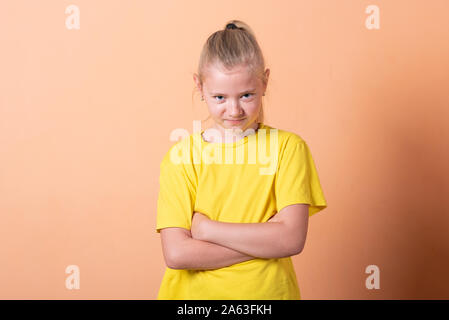 La jeune fille posa ses mains sur ses hanches, sur un fond orange. Banque D'Images