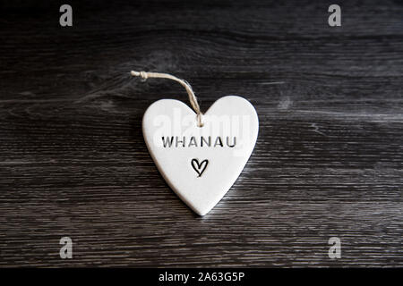 Ornement de forme coeur en céramique avec les Maoris whanau mot écrit. Famille sens qui peut comprendre des amis. Réalisés par des artistes en kiwi NZ. Mot de tous les jours Banque D'Images